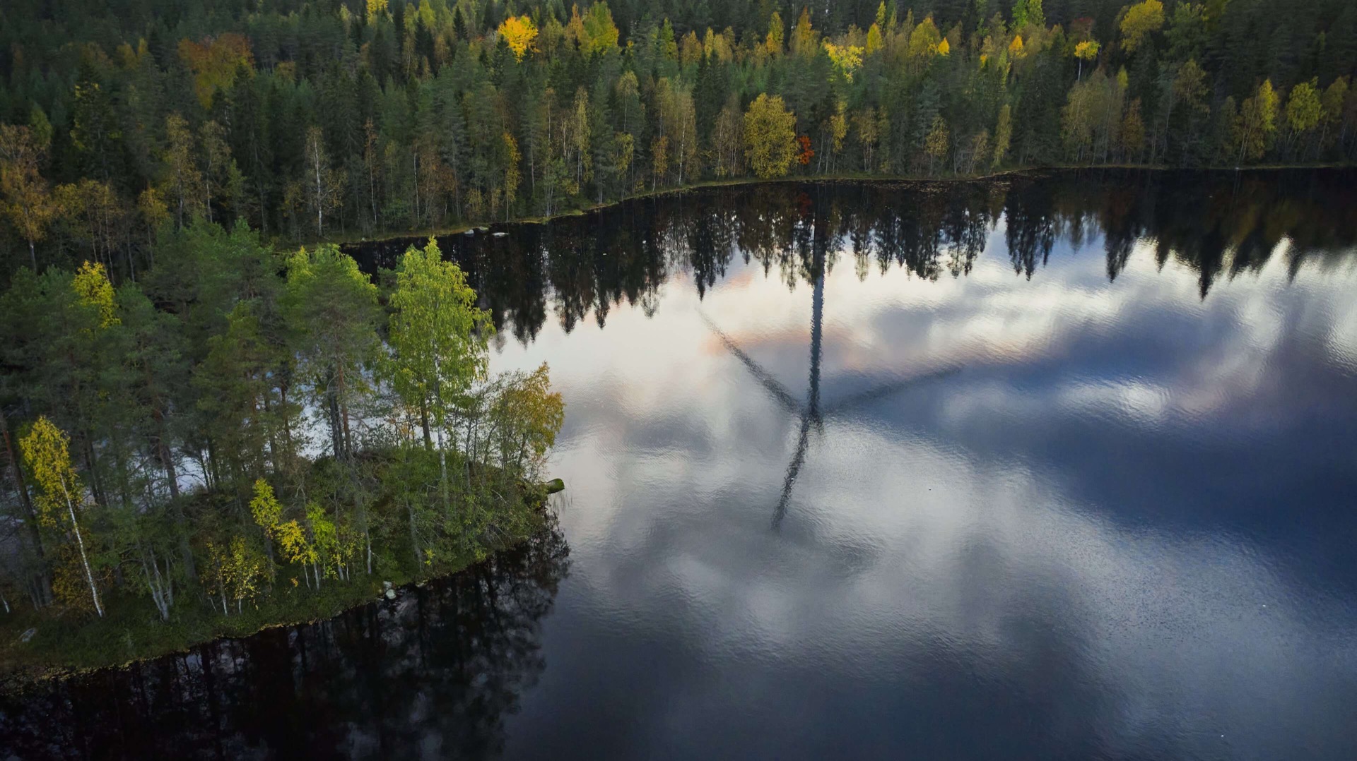 Wind turbines of BHM group's company Winda Energy in Finland with reflection over the lake in the forest.